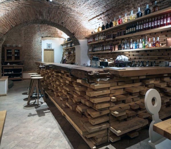 Cozy bar with brick arches and wooden decor, featuring stocked shelves and wooden bar stools