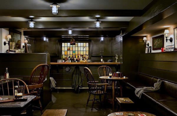 Cozy pub interior with wooden bar furniture, a bar counter, stained glass backdrop, and warm lighting
