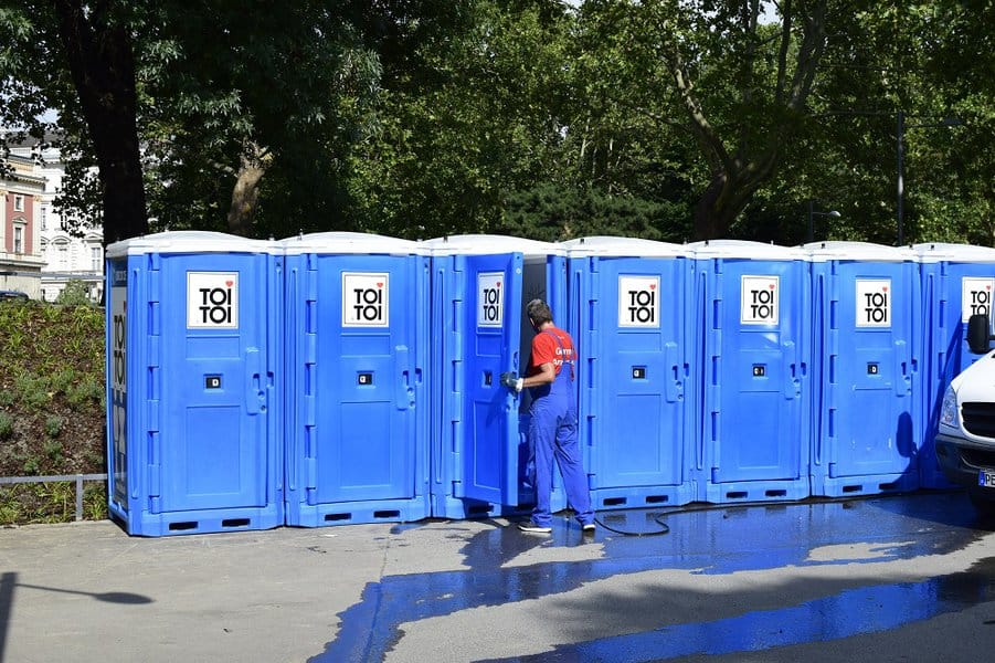 man cleaning the portable public toilets