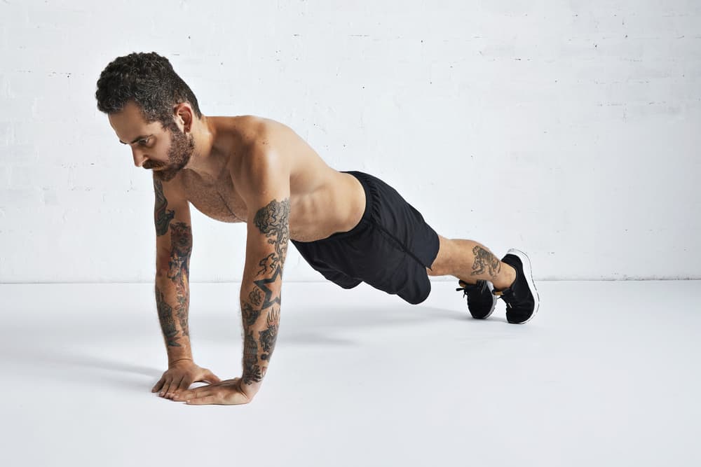 tattoed male athlete man doing diamond push up exercise