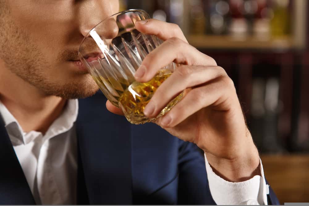 young man drinking whiskey in bar