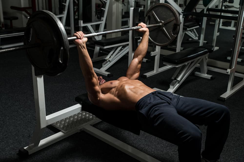mature man in gym doing barbell bench press exercise