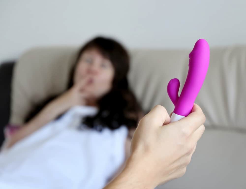 man holding dildo before couple going to sex in bed