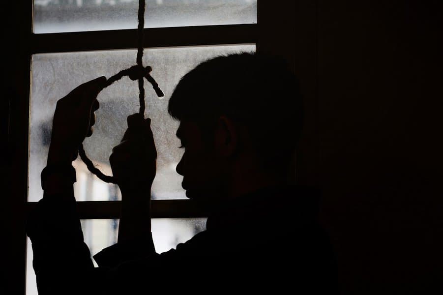man holding hangman noose in the dark room