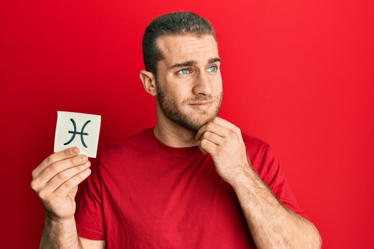 man holding paper with pisces zodiac sign while thinking about question