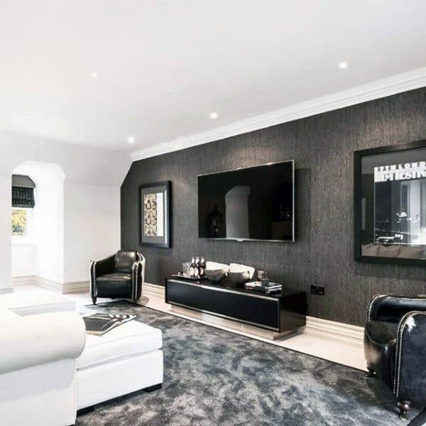 Contemporary living room with black accent wall, large TV, and leather armchairs.