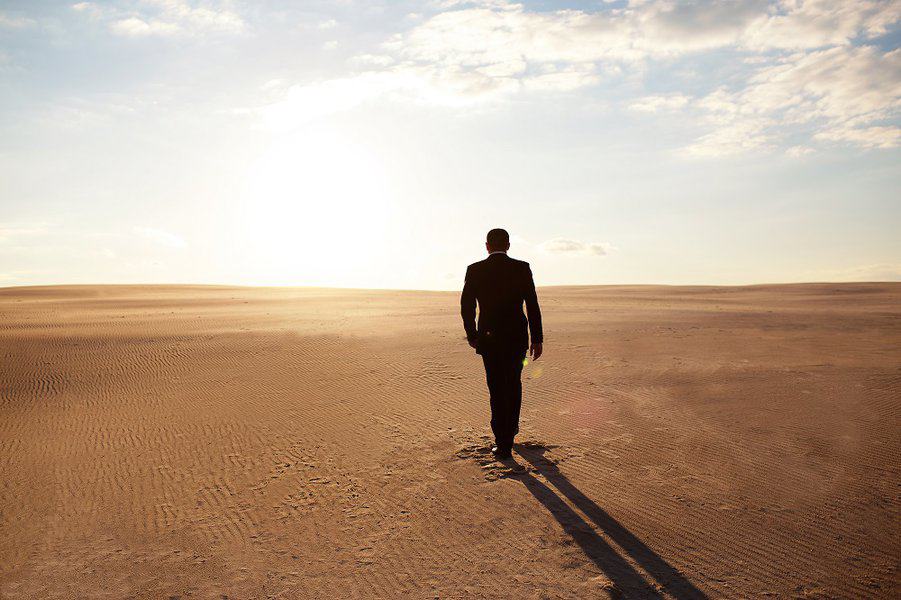 man in a suit walks through the desert