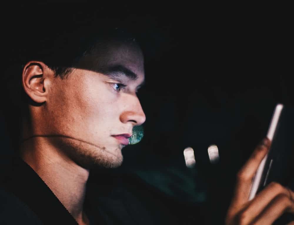 man looking at his phone while inside the car