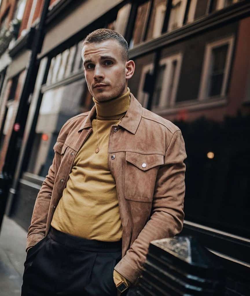 A man modeling a mustard-colored roll-neck shirt and a suede jacket