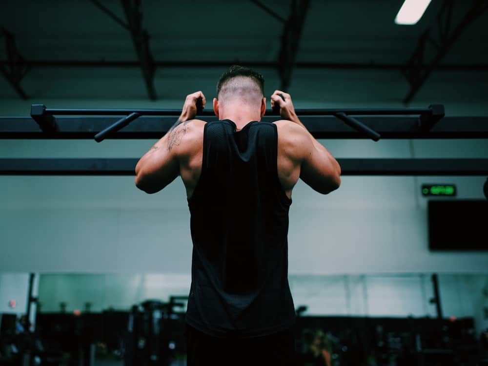 photo of the back of a man in a gym performing a chin up