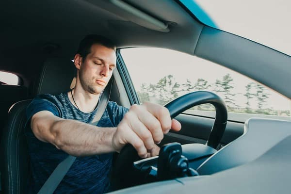 man pretending to sleep while driving