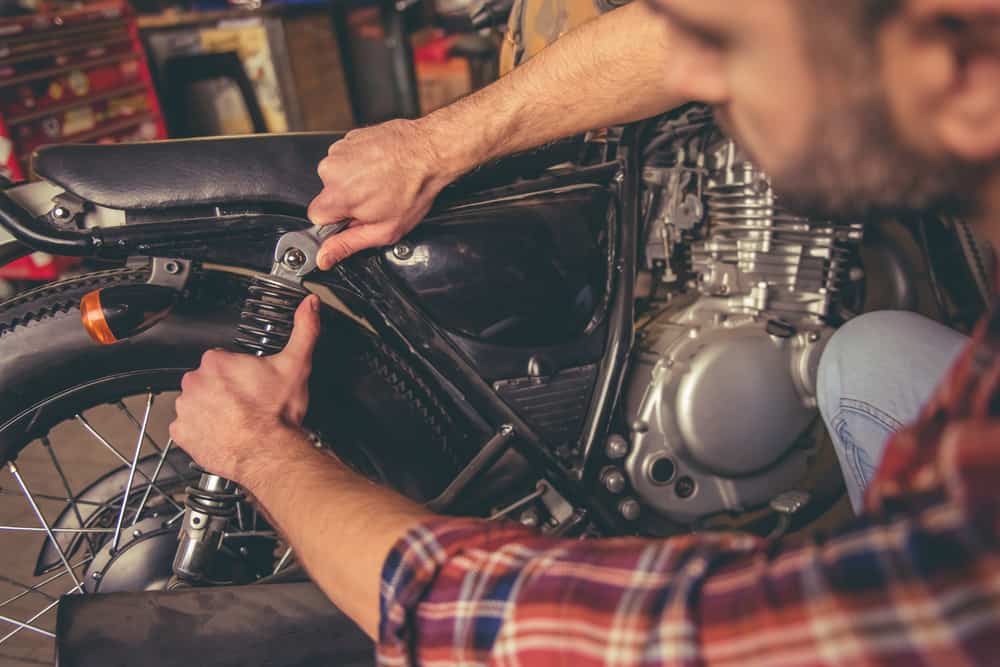 handsome young man is repairing a motorcycle in the repair shop