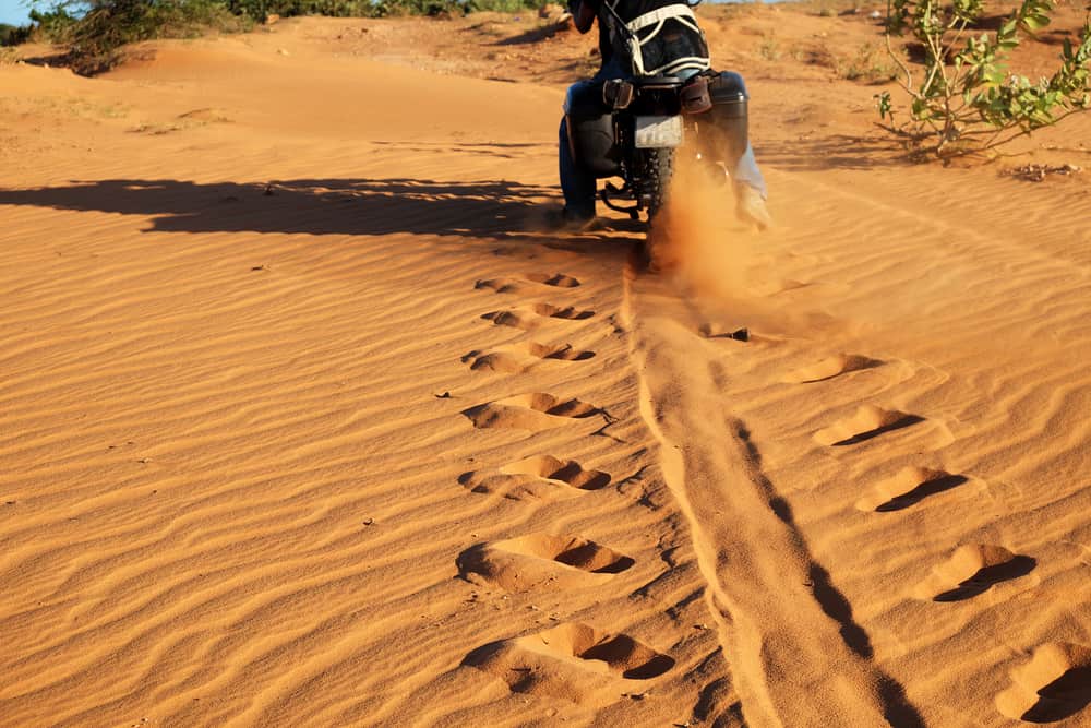 man ride motorbike on sand hill, wheel tracks on sand