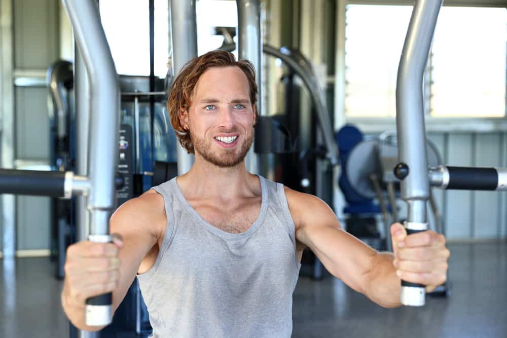 man training hard at fitness gym doing seated pec deck exercise