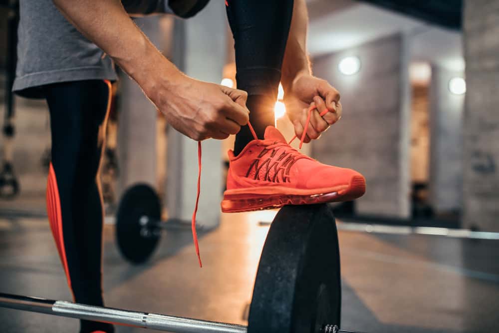 man tying his orange shoes shoelaces