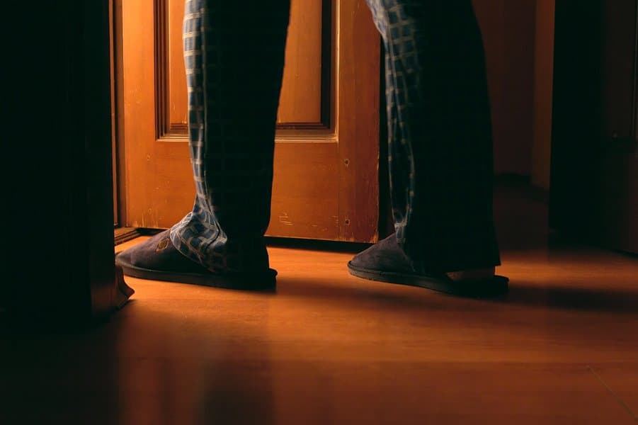 man walks to a bathroom at the night wearing slippers