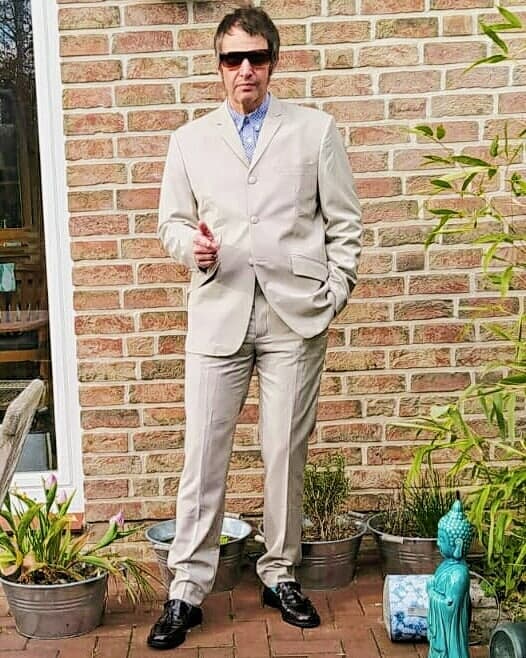 A man wearing a traditional stone-colored three-button mod suit