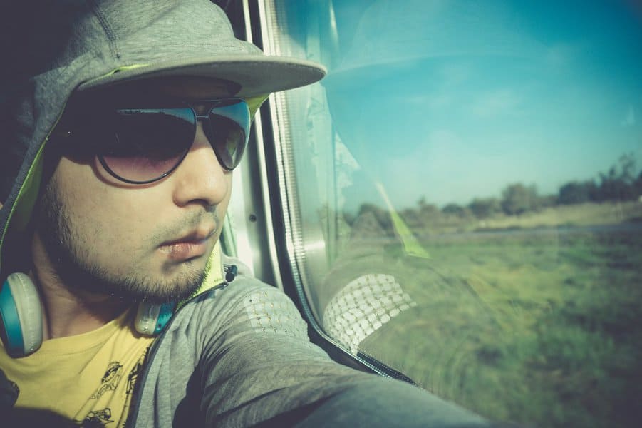 man wearing sunglasses looking through train window