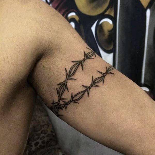 Man With Barb Wire Tattoo Wrapped Around Biceps Of Arm
