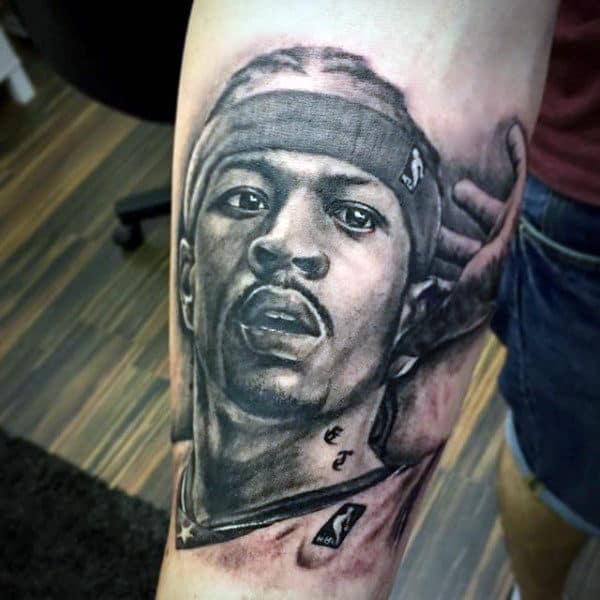 Forearm tattoo of a headshot of a man wearing a headband, with a wooden floor in the background