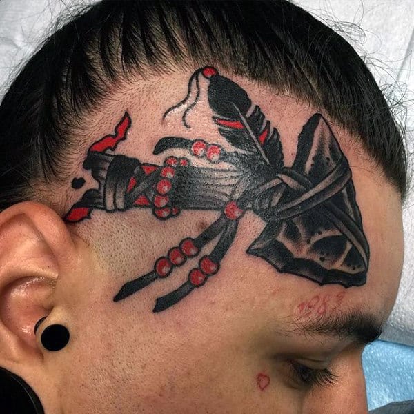 Man With Black Ink Tomahawk Tattoo On Head With Red Beads