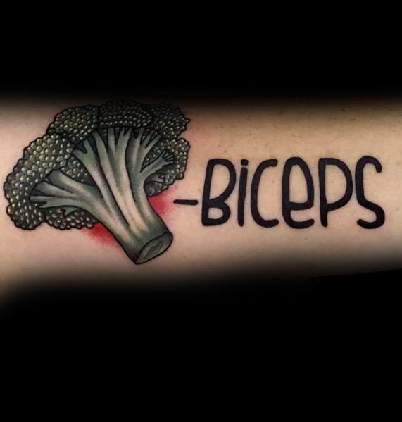 Humorous broccoli tattoo on the forearm with the text "-BICEPS," combining a playful fitness pun with bold shading and vibrant details.