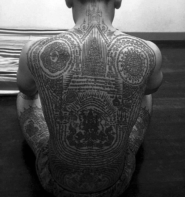 Man With Buddhist Scriptures And Symbols Tattoo On Full Back And Thighs