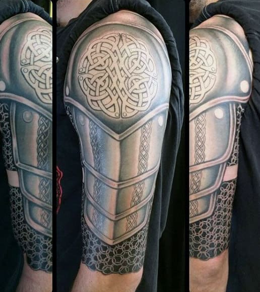 Arm tattoo resembling medieval armor with Celtic knot design on shoulder plate