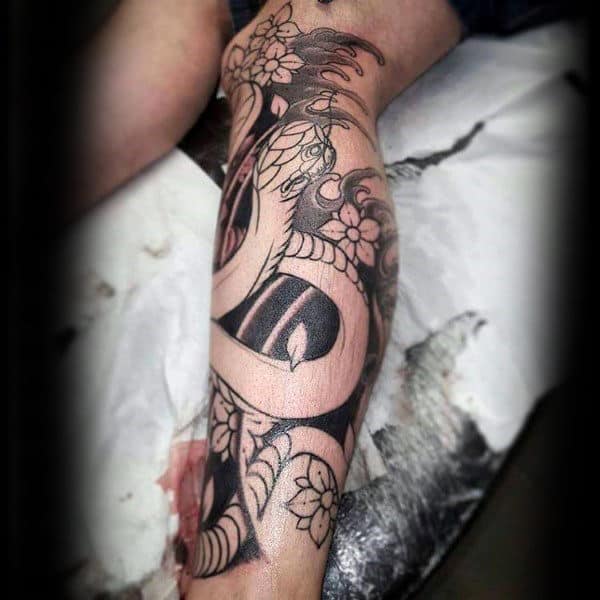 Black and grey leg tattoo featuring a coiled snake intertwined with cherry blossoms, bold shading, and intricate Japanese-style details