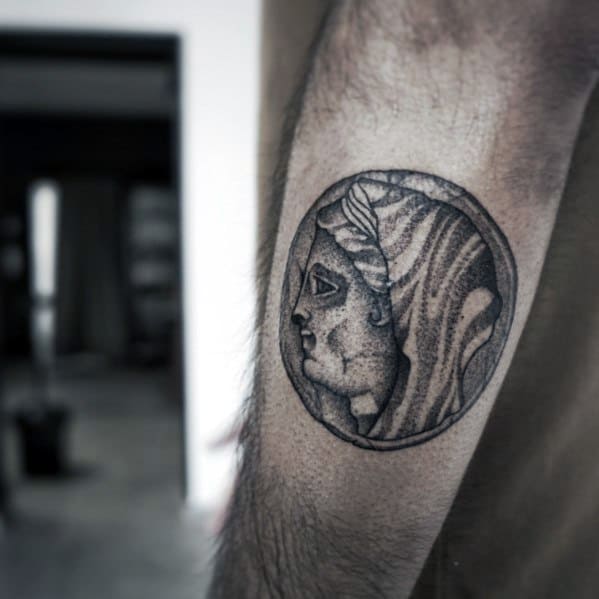 Realistic tattoo of an ancient Greek coin featuring a detailed profile of a goddess, with fine shading for a classic and historical look.