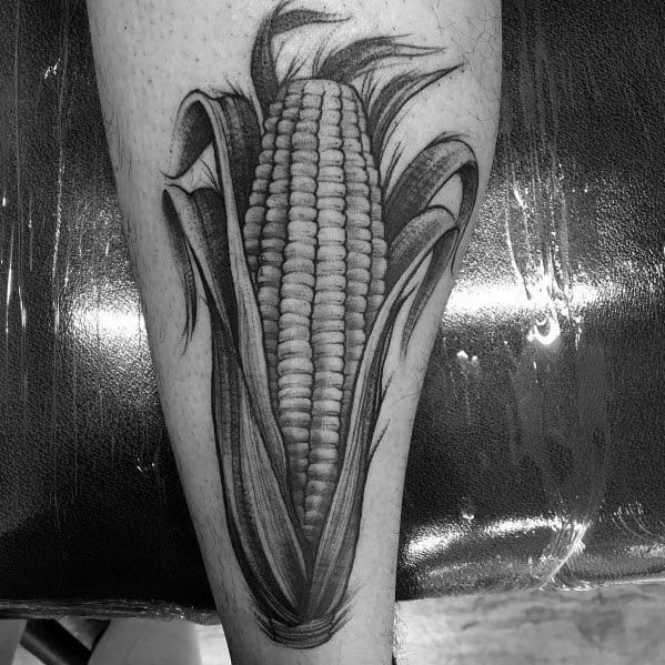 Black and gray tattoo of a realistic corn cob with detailed shading and textured husks, creating a bold and intricate design.