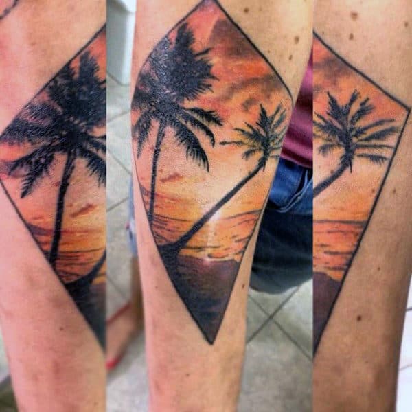 Tattoo of two palm trees against a vibrant sunset sky within a diamond-shaped frame
