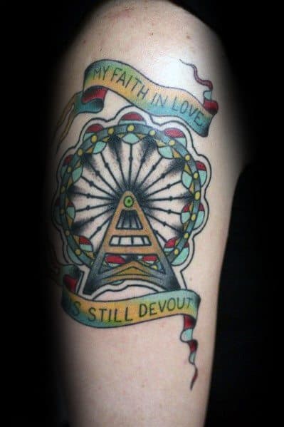 Traditional Ferris wheel tattoo with bold outlines, vibrant colors, and a ribbon banner reading "My faith in love is still devout," adding a sentimental touch.