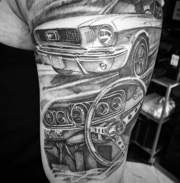 Realistic black and grey Ford Mustang tattoo on upper arm, featuring a detailed front view and classic interior dashboard with intricate shading.