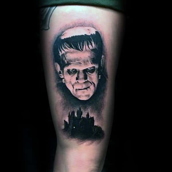 Man With Frankenstein Looking Down On Black Ink Castle Guys Thigh Tattoos