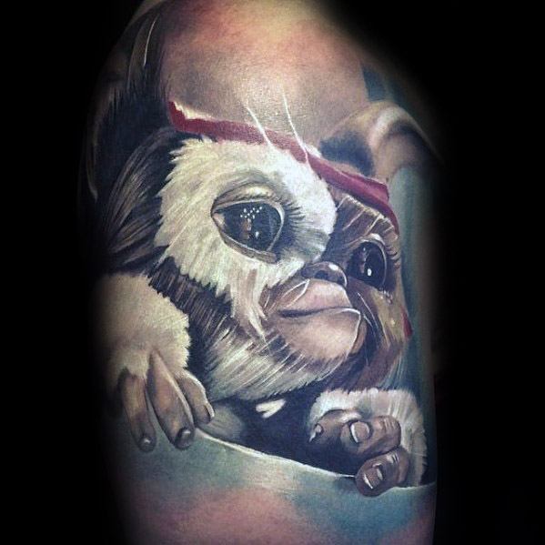Realistic Gizmo tattoo with detailed fur, expressive eyes, and a red headband, capturing a lifelike and heartwarming look.