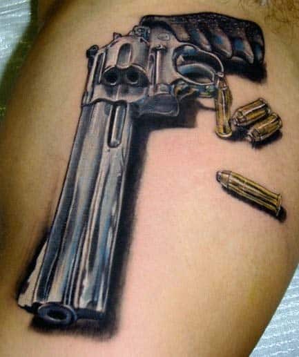 Man With Gun And Bullet Tattoos On Bicep