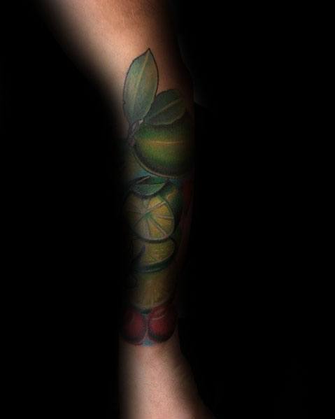 Vibrant fruit-themed sleeve tattoo featuring limes, cherries, and leaves, creating a bold and dynamic botanical design.