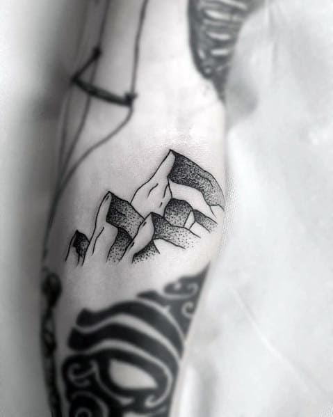 Minimalist mountain tattoo on the forearm, featuring bold outlines with dot shading for depth and a rugged, nature-inspired design.