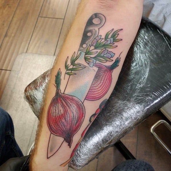Colorful forearm tattoo featuring a chef's knife, red onions, and herbs, blending realism with a modern artistic style and fine shading details.
