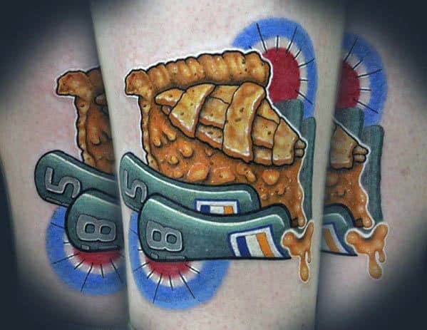 Golden-brown pie slice tattoo with a lattice crust, dripping filling, and a racing-inspired number 85 banner, blending food and speed themes
