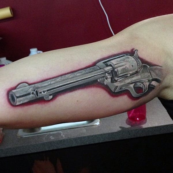 Man With Realistic Pistol Tattoo With Red Border On Forearms