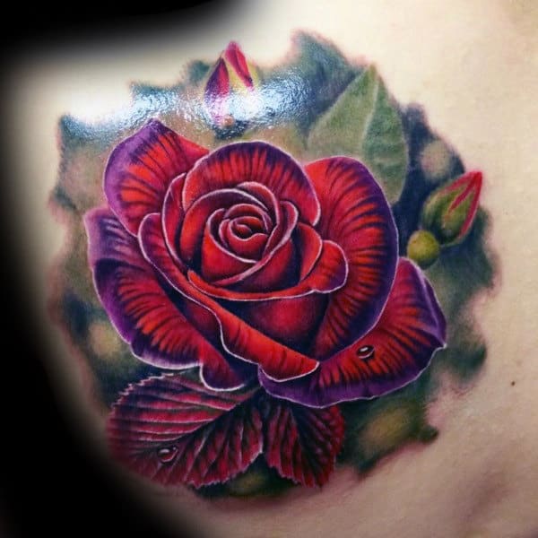 A vibrant red rose tattoo with green leaves and buds on a shoulder