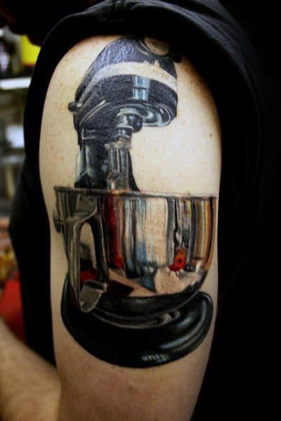 Tattoo of a metallic stand mixer with a highly reflective bowl, capturing realistic reflections and intricate details for a unique and striking design.