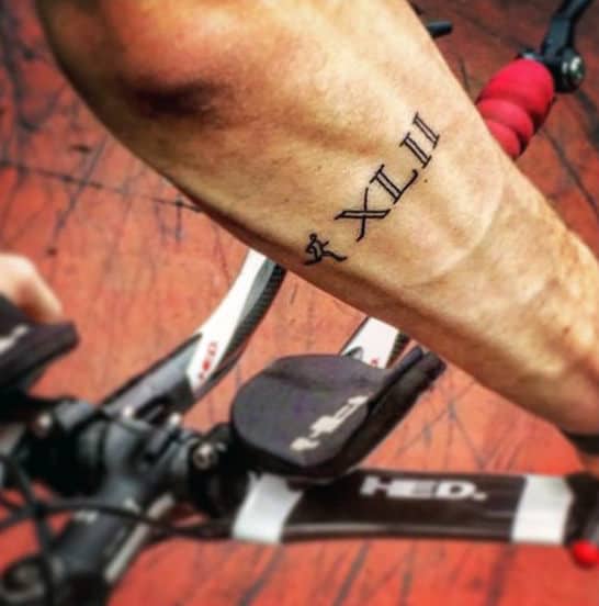Man With Running Roman Numeral Outer Forearm Tattoo