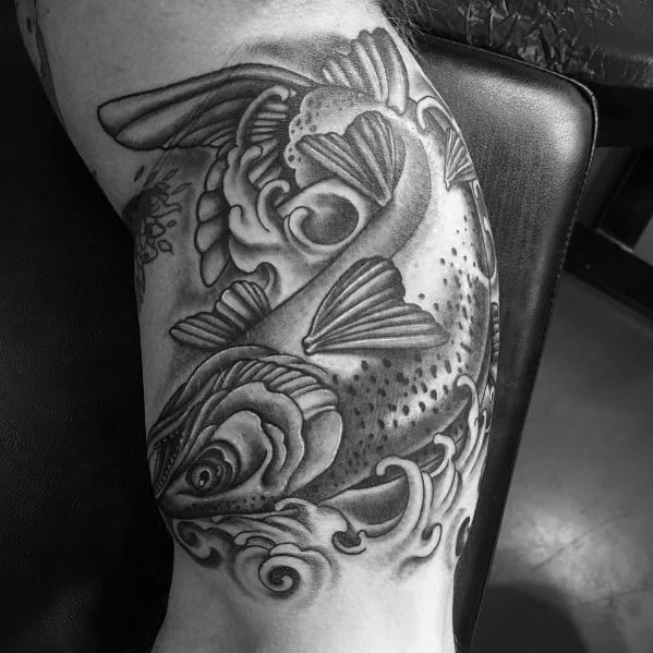 Black and grey tattoo of a leaping salmon with flowing water and bold shading, creating a dynamic and powerful design on the arm.