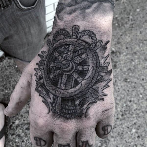 Man With Ship Wheel Tattoo And Water On Hand