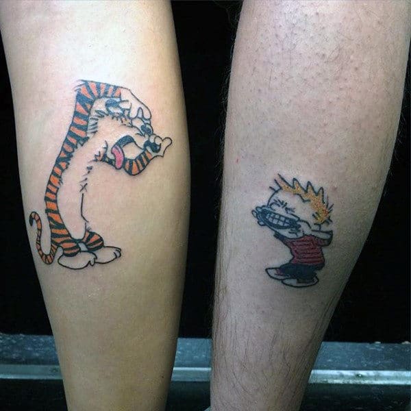 Man With Small Calvin And Hobbes Tattoos On Back Of Legs