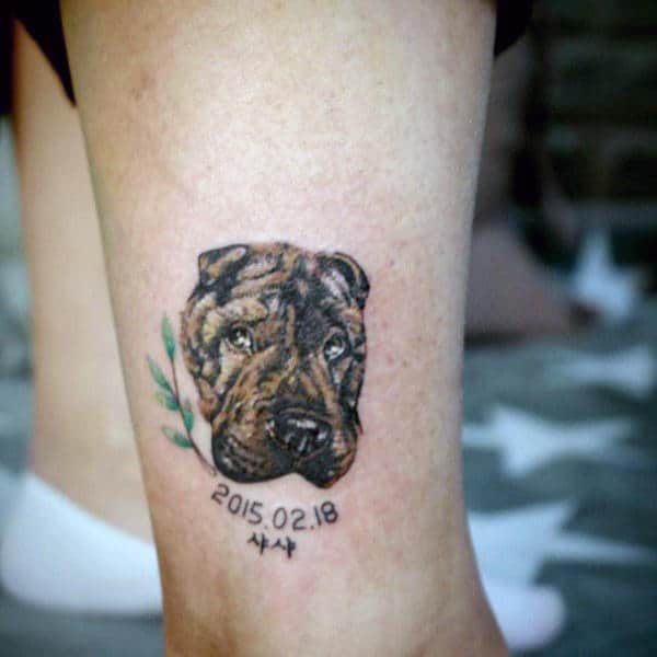 Man With Small Dog Face Tattoo On Leg