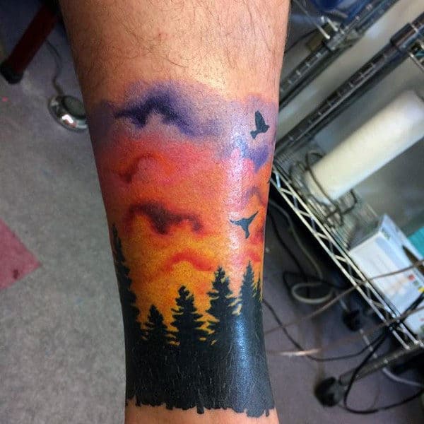 Man With Sunset Forest And Colorful Sunset Tattoo On Ankle